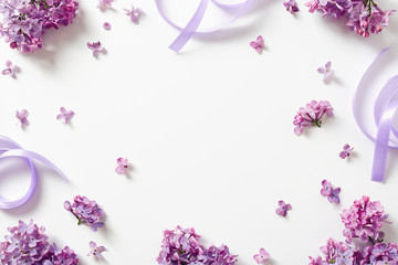 Decorative frame of beautiful purple lilac flowers and and satin ribbon.