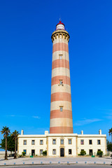Obraz premium Lighthouse of Praia da Barra during the day, with a clear blue sky. View of the lighthouse of Barra beach (Praia da Barra) in Aveiro, Portugal.