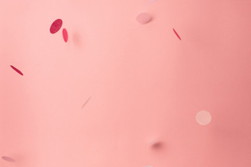 Pink confetti on pink background. Copyspace for text. Bright and festive holiday background.