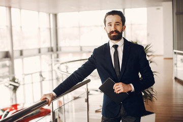 Man buying the car. Businessman in a car salon. Guy in a black suit