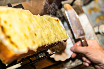 Raclette on the raclette grill is already grilled and spread with a knife on the bread and it...