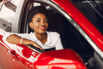 Woman buying the car. Lady in a car salon. Elegant black girl