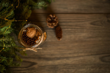Christmas gift, spices and decor in the glass jar, pine cones, fir branches on wooden brown background. Copy space for your text. Holidays, winter, Christmas presents concept. Toned image. Soft focus.