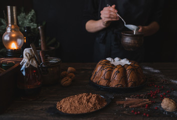 Cooking homemade cake Christmas Eve at home rustic kitchen. Woman's hands make pudding. Ingredients for cooking christmas baking on dark wooden table. Merry Christmas and Happy Holidays! Toned image.