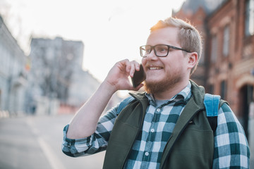 Portrait of a young man with a phone against the background of a European sunny street.