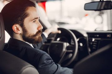 Man buying the car. Businessman in a car salon. Guy in a black suit