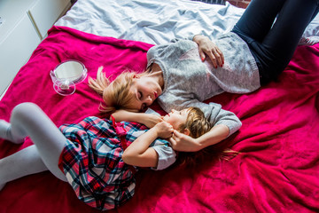 Mother and daughter have a fun in a bed at home