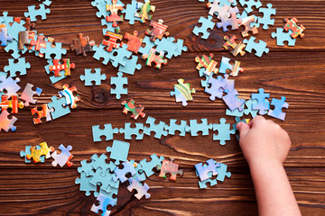 Puzzles, child's hand on wooden table background. preschool education, Board puzzle game.