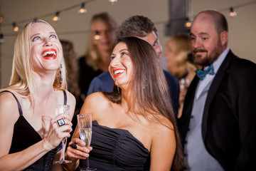 Two Laughing Women Being Watched by Men at Party