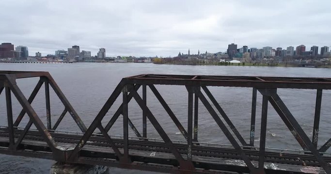 Drone footage over the flooded Ottawa River going over The Price of Whales Bridge facing downtown.