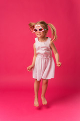 happy baby girl smiling in sunglasses on pink background. the concept of childhood