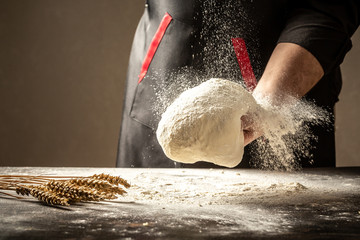 man clapping and sprinkling flour over dough on table. White flour flying into air. space for text