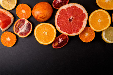 Top view, flat lay. Sliced citrus on a black background. Copy space. Fruits are laid out on top.