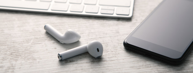 Smartphone, headphones and computer keyboard on a white wooden background. Technology