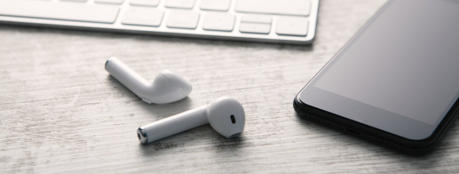 Smartphone, headphones and computer keyboard on a white wooden background. Technology