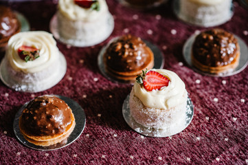 Delicious sweet chocolate and vanilla cakes with strawberries on purple background. Festive sweet table with baking.