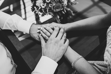 The Bride and groom holding hands. Stylish wedding bouquet of flowers. Black and white photo.