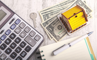 apartment building, dollars and calculator on a wooden table