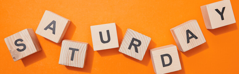 panoramic shot of wooden cubes with letters on orange surface