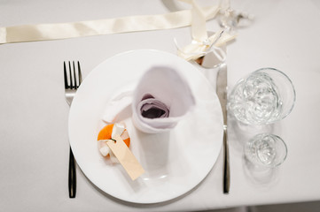 Serving, setting table. One plate and silverware cutlery  linen napkin are decorated with ribbons and orange. Wedding table decoration. Artwork. flat lay. top view.