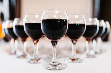 Glass of red wine on a table. Many glass wine on bar counter. Glasses with wine. Filled with half and stand on the holiday table. Furshet. selective focus.