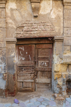 Broken wooden door on grunge stone bricks wall in abandoned Darb El Labana district, Cairo, Egypt