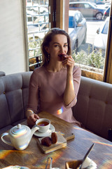 girl in a pink jacket sitting in a restaurant with a Cup of tea