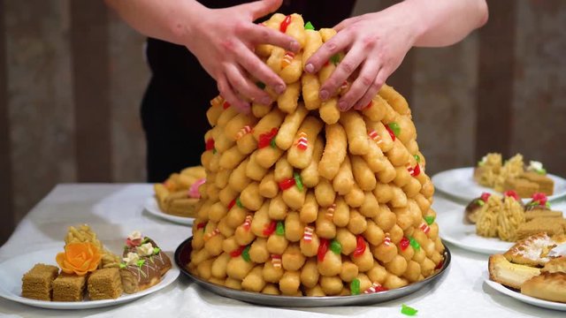 Chak-chak traditional asian sweet dessert - fried dough with honey. Oriental sweets. The waiter in the restaurant lays out the dessert in plates. Traditional dessert on nikah Muslim wedding.