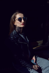 girl in a leather jacket and sunglasses with kinesiology tape standing in the street