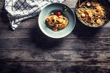 Pasta spaghetti on plate and pan with shrimp tomato sauce toatoes and herbs. Italian or mediterranean cuisine