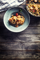 Pasta spaghetti on plate and pan with shrimp tomato sauce toatoes and herbs. Italian or mediterranean cuisine