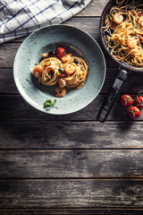 Pasta spaghetti on plate and pan with shrimp tomato sauce toatoes and herbs. Italian or mediterranean cuisine