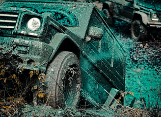 Bottom view to big offroad car wheel on country road and mountains backdrop. Offroad vehicle coming out of a mud hole hazard. Drag racing car burns rubber. Extreme. Tires in preparation for race. © Volodymyr