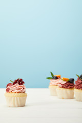selective focus of cupcakes on white surface isolated on blue