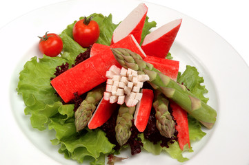 Crab sticks on a plate with lettuce and tomatoes on a white background