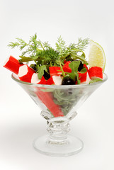 Crab glass sticks with lettuce, lemon slices, olives on gray background