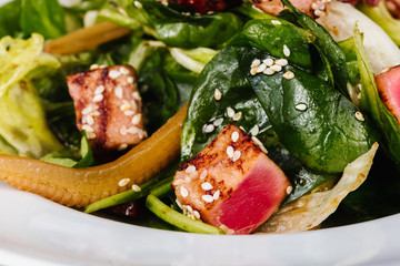 Salad with corn, meat, salmon, green leaves, tomatoes, oil and spices