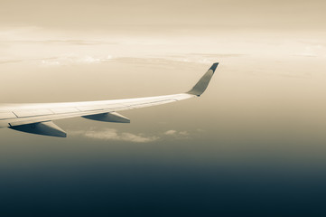 Fototapeta na wymiar cloudy sky and airplane wing as seen through window of an aircraft