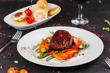 Fried pork with vegetables: green beans, carrots, paprika, garlic, greens, tomato and a glass of red wine,