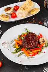 Fried pork with vegetables: green beans, carrots, paprika, garlic, greens, tomato and a glass of red wine,
