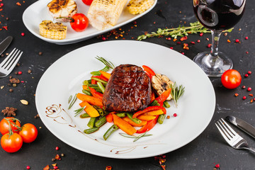 Fried pork with vegetables: green beans, carrots, paprika, garlic, greens, tomato and a glass of red wine,