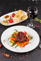 Fried pork with vegetables: green beans, carrots, paprika, garlic, greens, tomato and a glass of red wine,