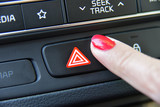 woman pressing red triangle car hazard warning button