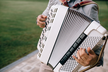 Fototapeta na wymiar Closeup detail of hands playing a white accordion instrument