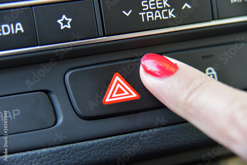 woman pressing red triangle car hazard warning button