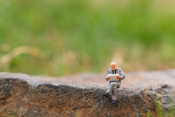 Miniature people: Business man reading newspaper with copy space
