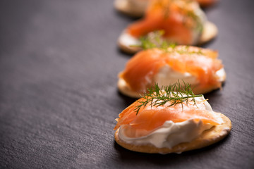 Canapes with salmon isolated on black background