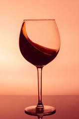 A wine glass with a splash of wine on a yellow background. A glass on the bar in a cafe, restaurant, nightclub or disco.