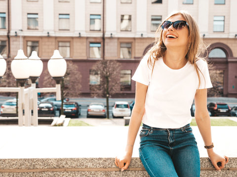 Portrait of beautiful smiling blond model dressed in summer hipster  clothes. Trendy girl posing in the street background. Funny and positive woman in sunglasses