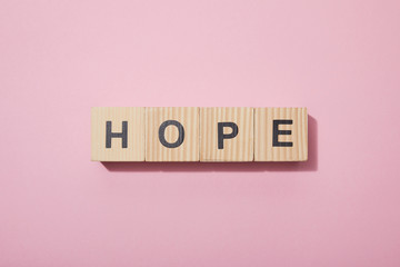 top view of wooden cubes with letters on pink surface